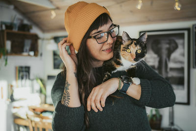 Young woman carrying cat on shoulder