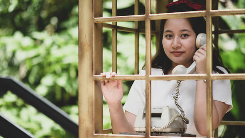 A smiling girl posing with a classic phone while traveling, she smiles.