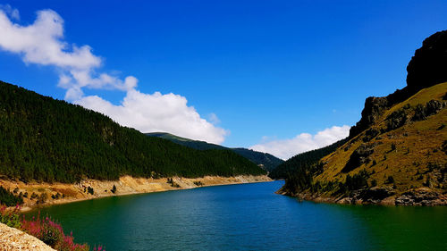 Scenic view of lake by mountains against blue sky