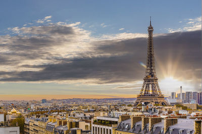 Aerial view of buildings in city against cloudy sky