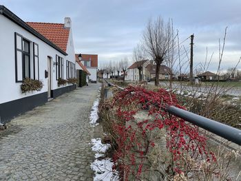 Footpath amidst buildings against sky during winter