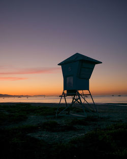 Lifeguard hut on beach against clear sky at sunset