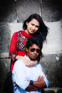 Portrait of smiling young couple against wall