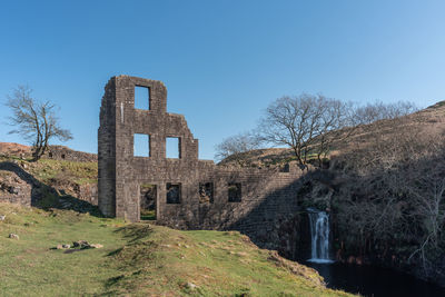 Low angle view of old ruin building against blue sky