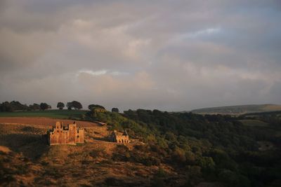 Built structure on landscape against cloudy sky