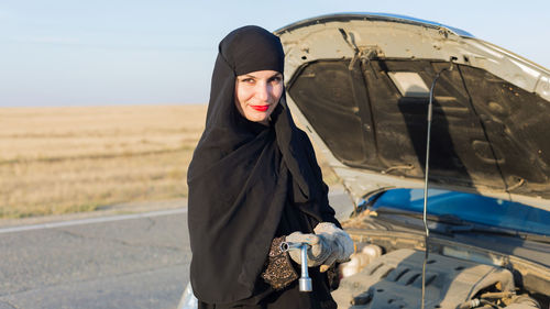 Young woman wearing sunglasses standing against the sky