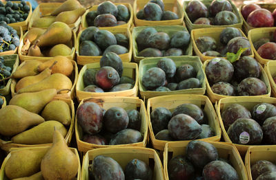 Plums and pears arranged in boxes at market for sale