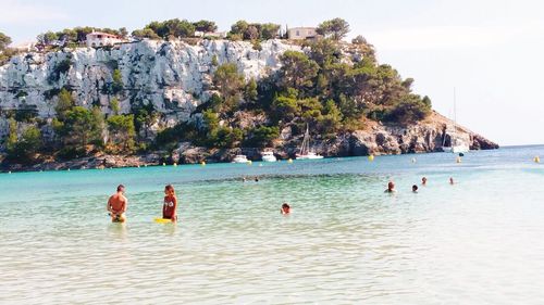 People enjoying at beach against sky