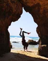 Woman doing handstand at beach against clear sky