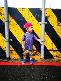 Cute boy standing against striped pattern on wall