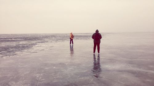 People playing on beach against clear sky