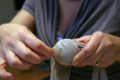 Midsection of woman stitching sock at home