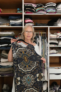 Senior woman choosing dress in her room 