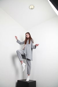 Portrait of young woman standing against wall