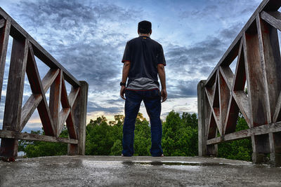 Low angle view of men standing against cloudy sky