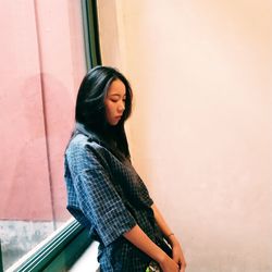 Beautiful young woman standing against wall