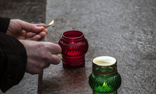 Cropped hands igniting lamps at memorial