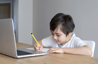 Boy writing on table at home