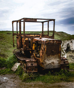 Abandoned train on field against sky