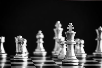 Close-up of chess pieces on board against black background