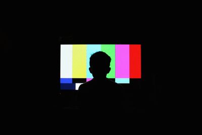 Silhouette of boy in front of television screen