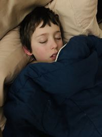 Boy sleeping on bed at home