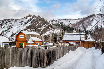 Snow covered houses against snowcapped mountains