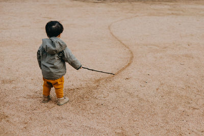 Side view of boy standing on sand at beach