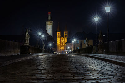 Illuminated street amidst buildings at night