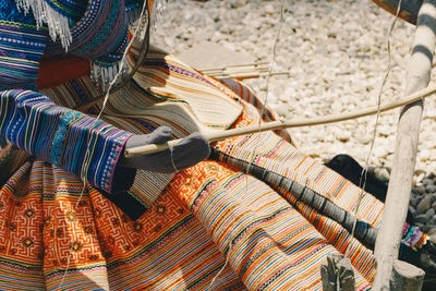 High angle view of person in traditional clothing weaving during sunny day