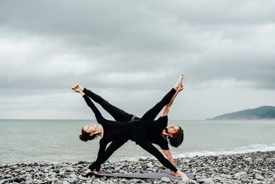 Full length of women exercising at beach