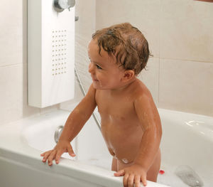 Child bathing in tub at home with foam