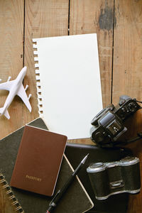 Directly above shot of diary with camera and binoculars on table