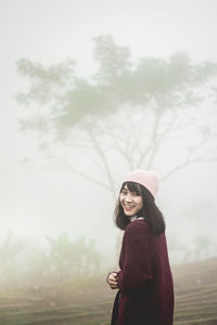 Portrait of smiling woman standing against trees