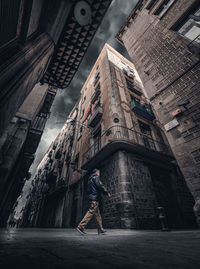 Low angle view of woman standing on alley amidst buildings in city