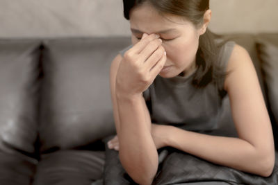 Midsection of woman sitting on sofa at home