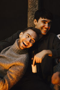 Smiling male friends looking away at balcony