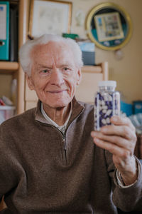 Smiling man holding medicines in bottle