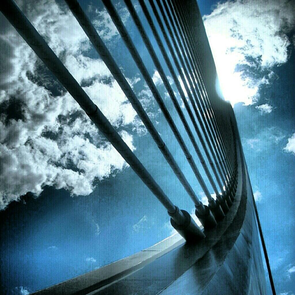 sky, glass - material, low angle view, reflection, window, sunlight, part of, built structure, day, railing, cropped, no people, cloud - sky, transparent, outdoors, transportation, cloud, architecture, tree, close-up