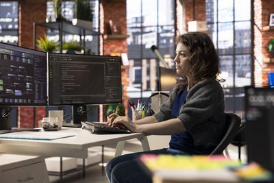 Side view of young woman using mobile phone in office