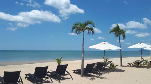 Deck chairs on beach against sky