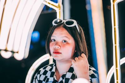 Portrait of woman by illuminated lighting equipment at night