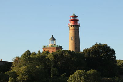 Lighthouse by sea against clear sky