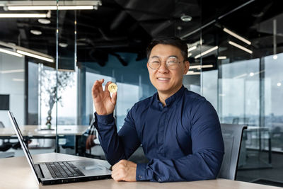 Portrait of businessman using laptop at office