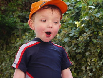 Close-up of boy making face while standing by plants at park