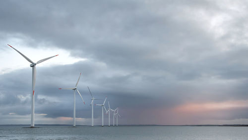 Wind turbines in sea against sky