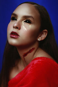 Close-up of girl wearing spooky make-up against blue background