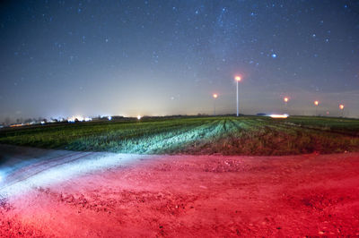 Scenic view of illuminated field against sky at night