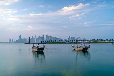Doha skyline seen from mia park and three dhow boats in the foreground.