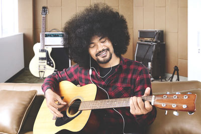 Smiling young man playing guitar in studio